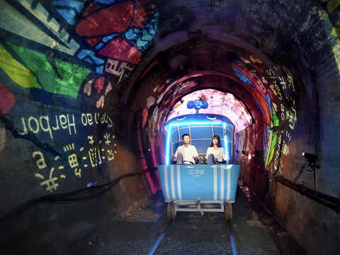 騎進深澳鐵道自行車光隧道，投影燈映照周邊特色景點，彷彿在光影中展開一場深澳小旅行。