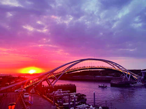 桃園竹圍漁港夕陽餘暉灑落海面，漁港天橋與港灣景致交織出浪漫迷人風光。