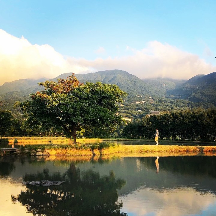 夕陽的餘暉撒下金光，清澈如鏡的湖面，倒映出遠山、綠樹與藍天，宛如人間仙境。