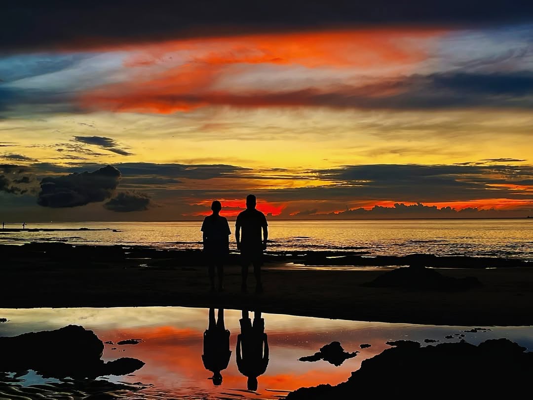 兩人並肩看海，倒影映在水面上，連時間都靜止了