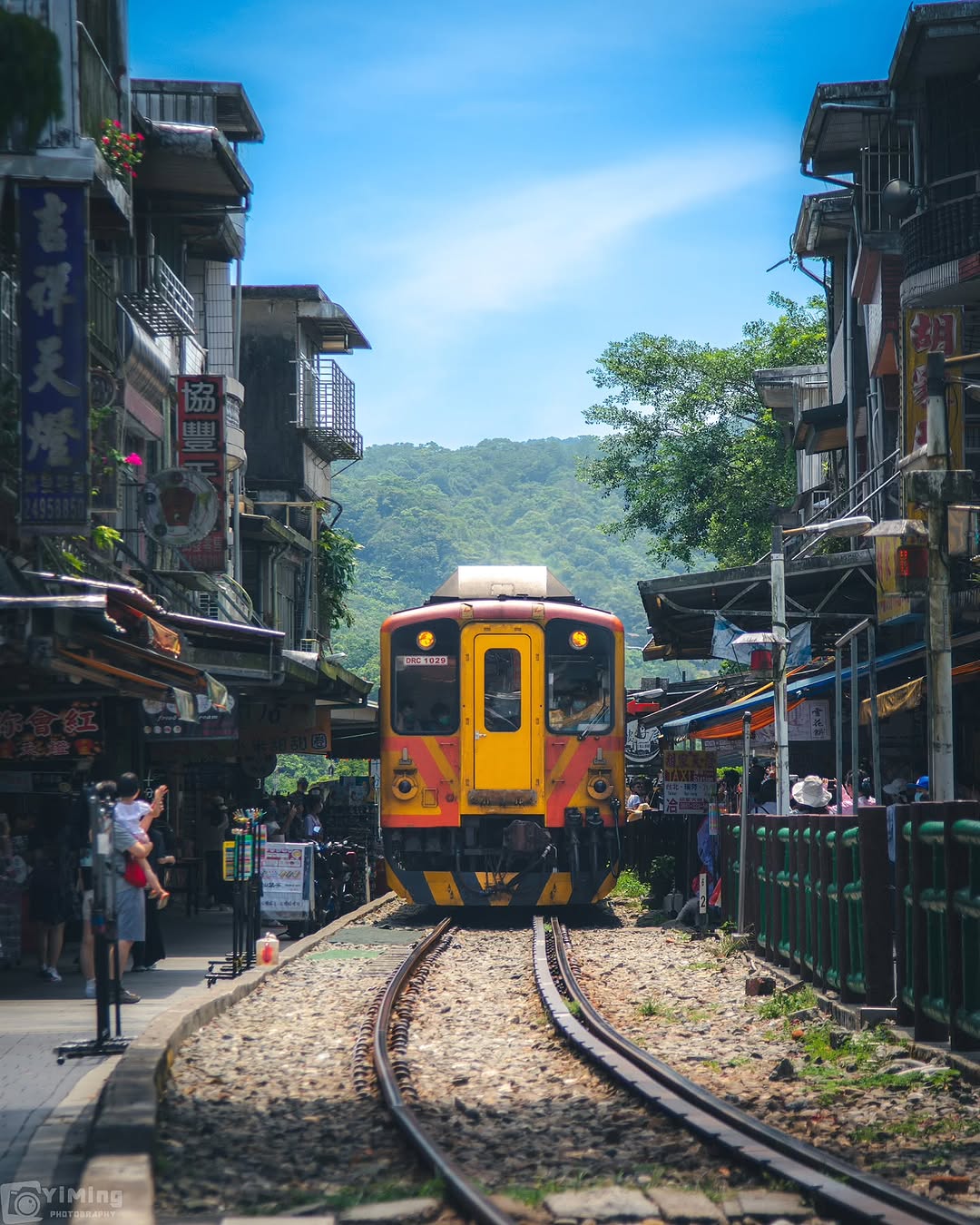 伴隨著清脆的鳴笛聲，黃澄澄的平溪線列車緩緩駛入街景