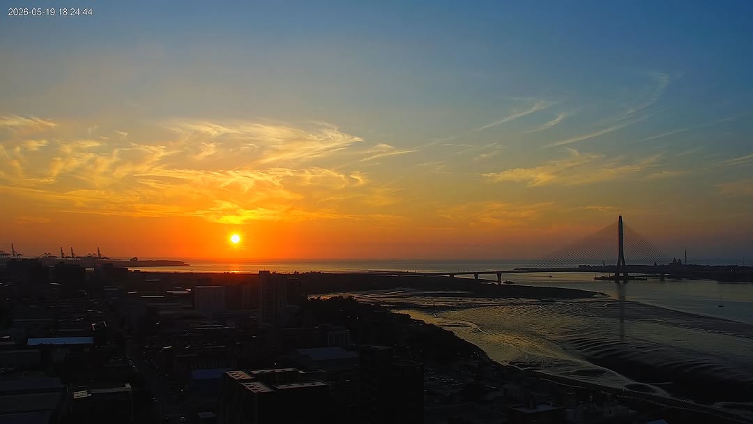 天邊的雲朵像是厚實的棉花糖卻擋不住夕陽在海平線掀起的璀璨浪潮 透過即時影像的鏡頭，我們捕捉到了八里左岸最令人心動的一幕——耀眼的金黃光芒與暮色交織，將整座淡水河口渲染得如詩如畫