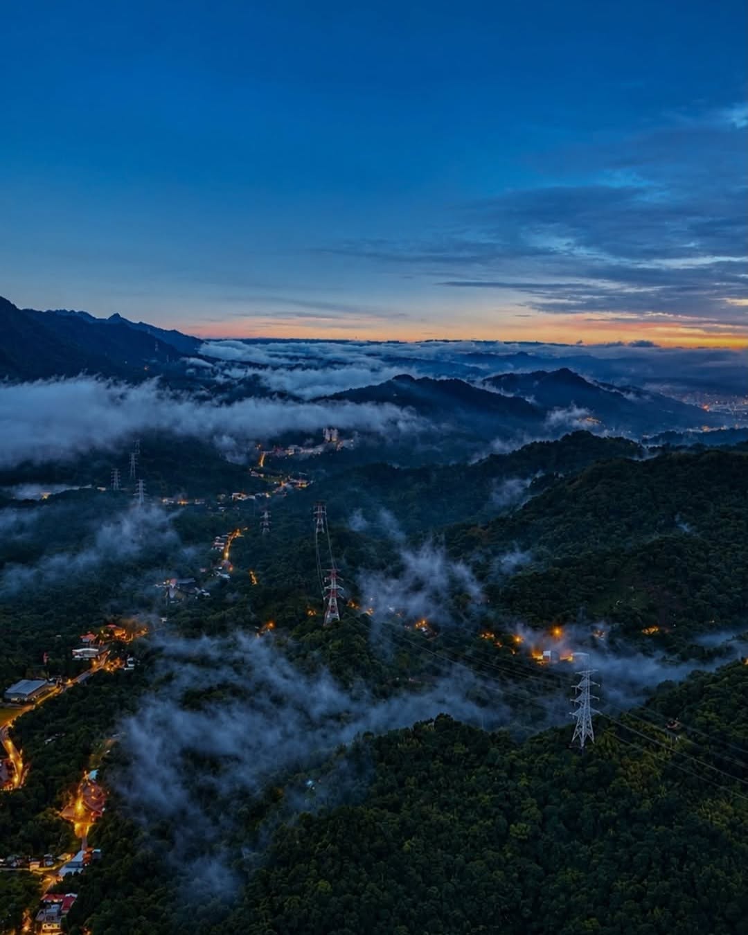 翻湧的雲海如輕紗般披掛在山脊上，與蜿蜒而上的電力塔、暖黃色燈火交織，拼湊出土城最迷人的深夜幾何學