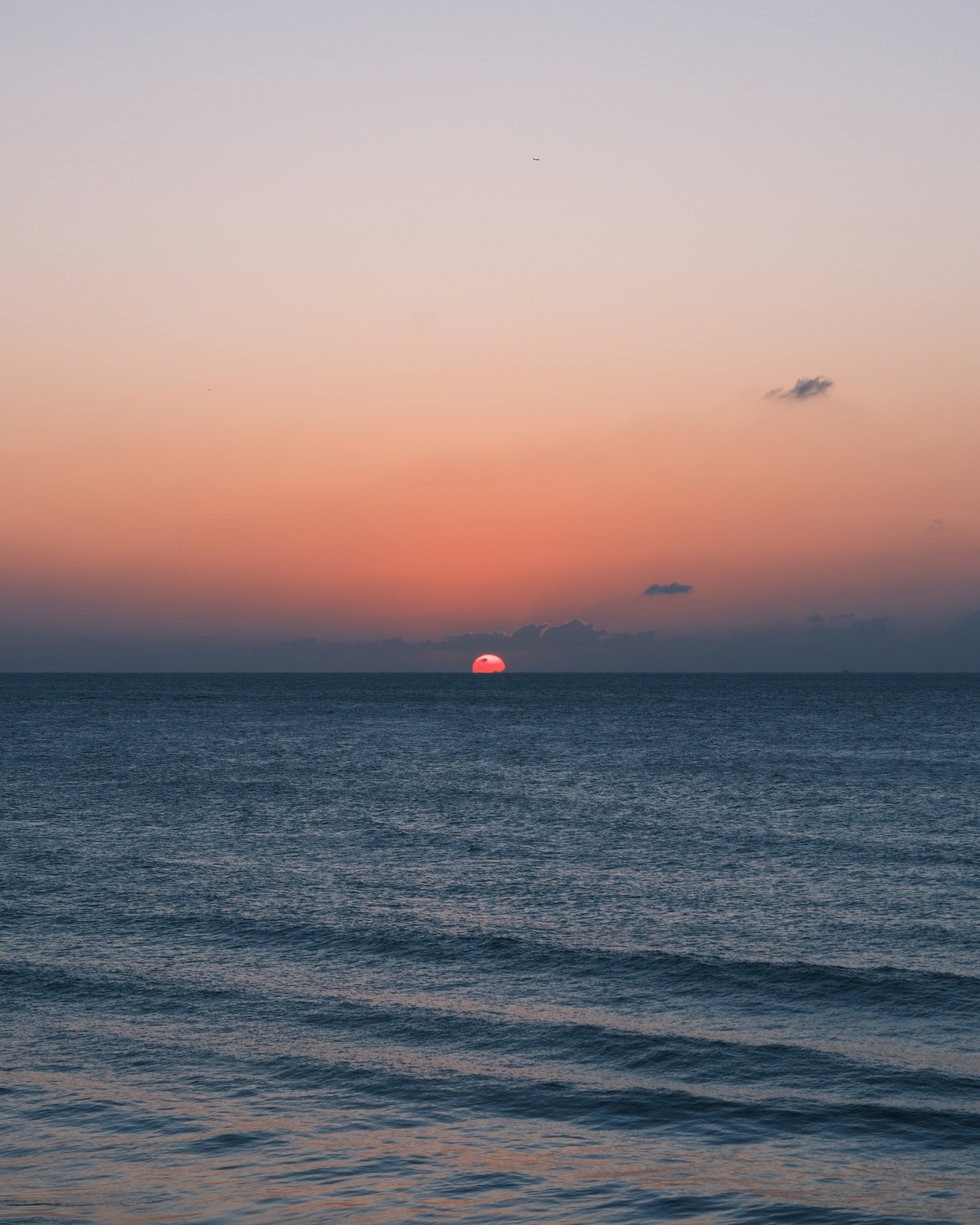 夕陽緩緩沒入湛藍的波光之中，將海平面暈染成一片溫柔的金橙色漸層